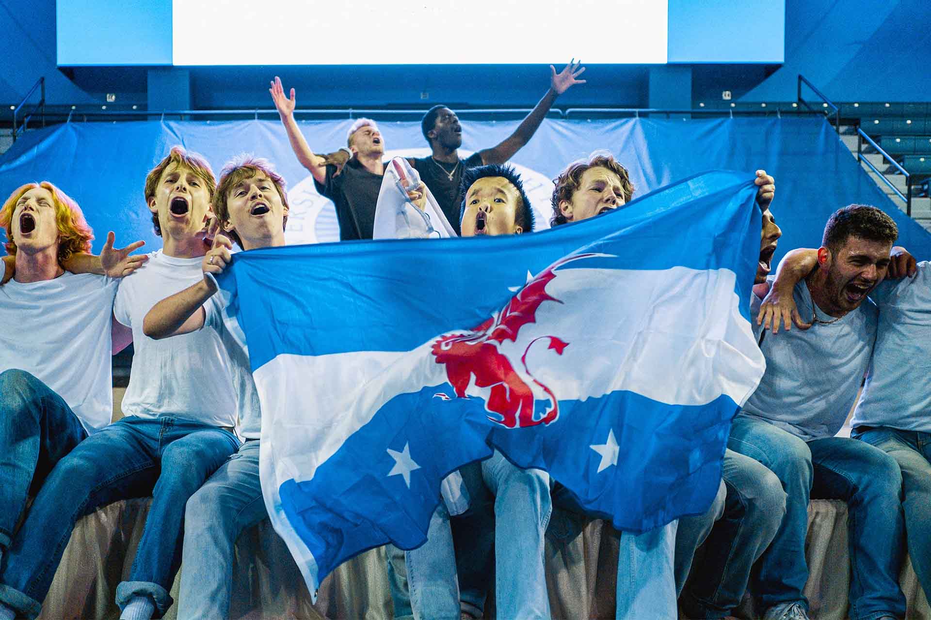 A group of collegiate men singing while holding a Beta Theta Pi flag