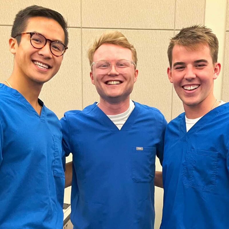 Three men in medical scrubs pose for a group photo