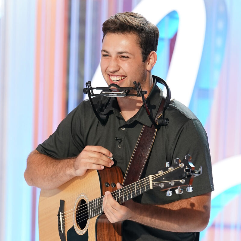 Owen Eckhardt, Oklahoma State '26, smiles while holding his guitar on set after his American Idol audition.